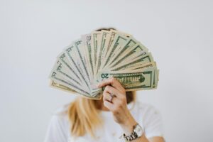 woman holding cash, several 20 dollar bills