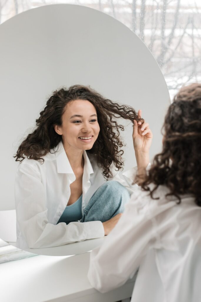 SonderBeaut woman with curly hair looking in the mirror and tugging at her hair