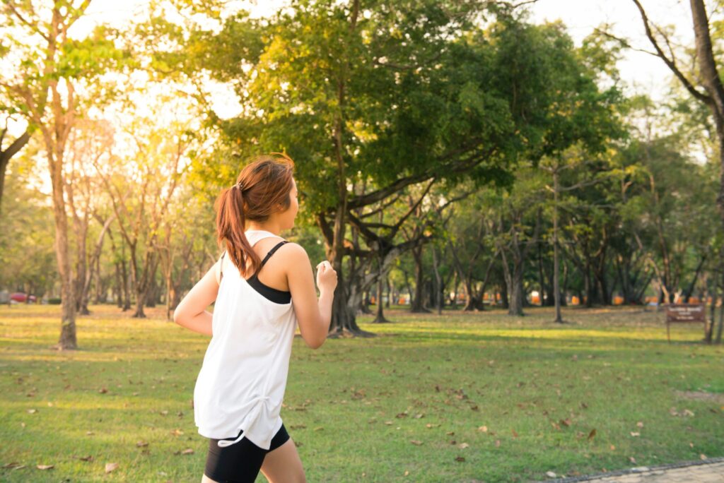woman running outside in daylight with trees in the background