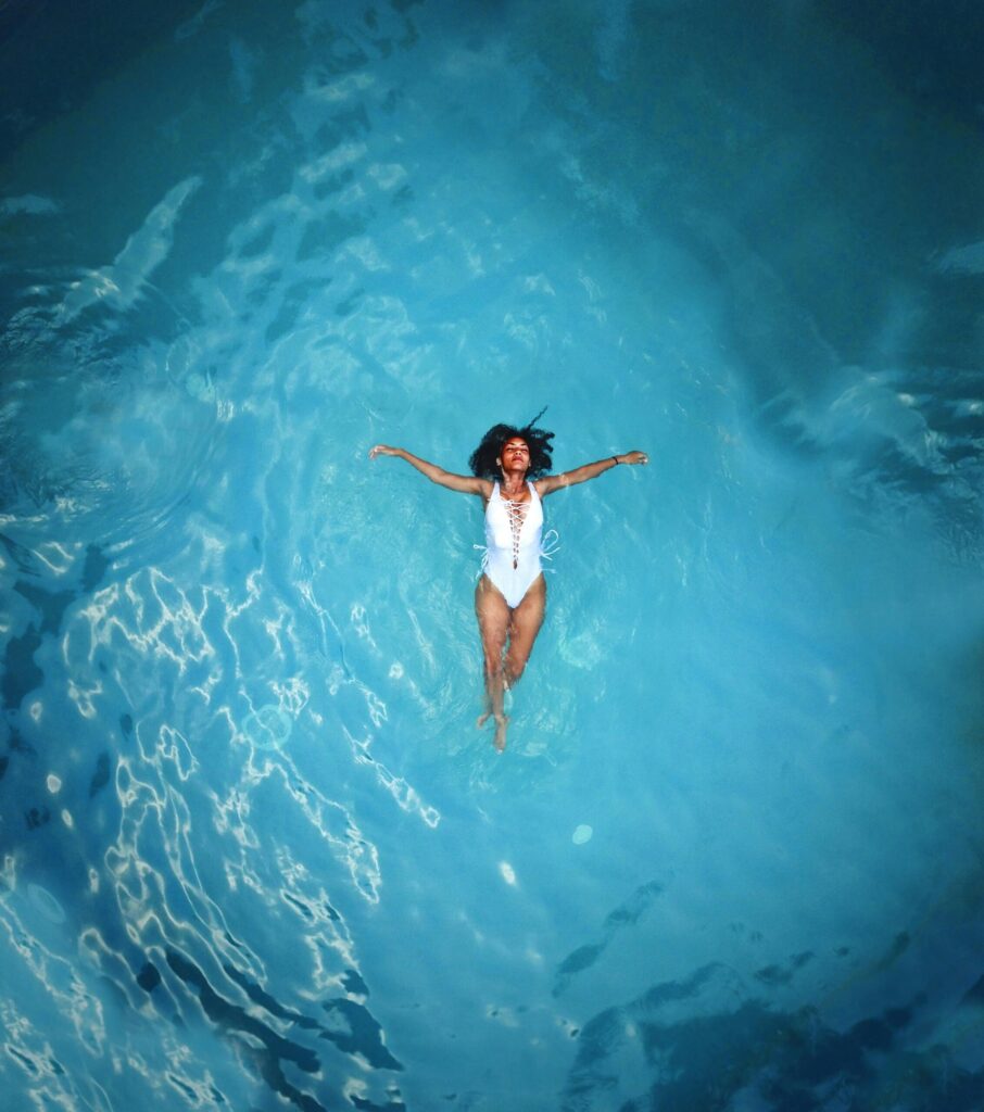 SonderBeaut woman floating in a white bathing suit in the middle of vast blue water