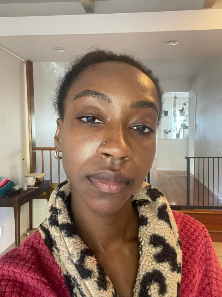 SonderBeaut woman with dark skin showing skin wearing red robe with the elta md uv clear deep tinted sunscreen on