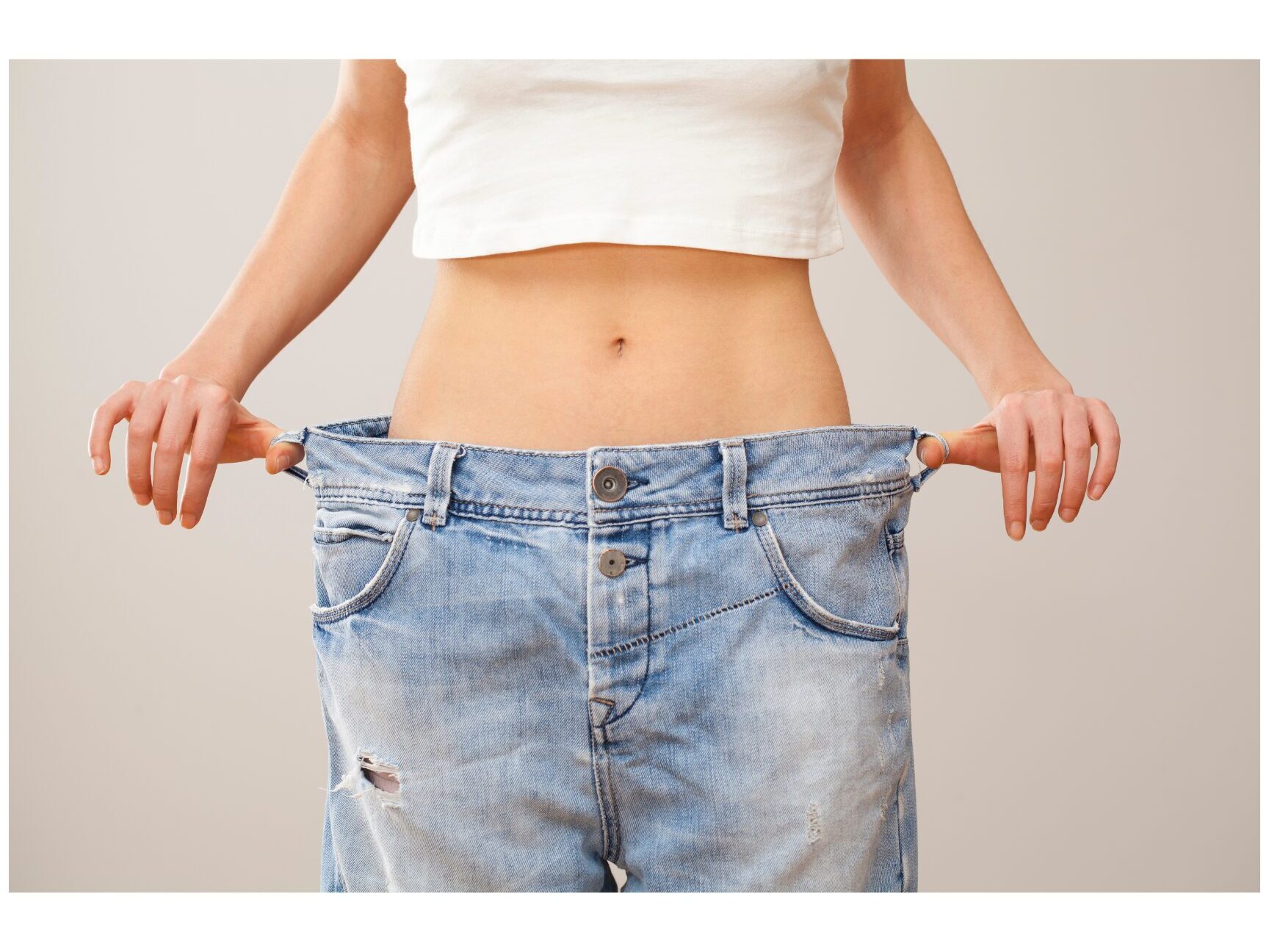 SonderBeaut woman exposing her abdomen and pulling at her jeans to show her weight loss
